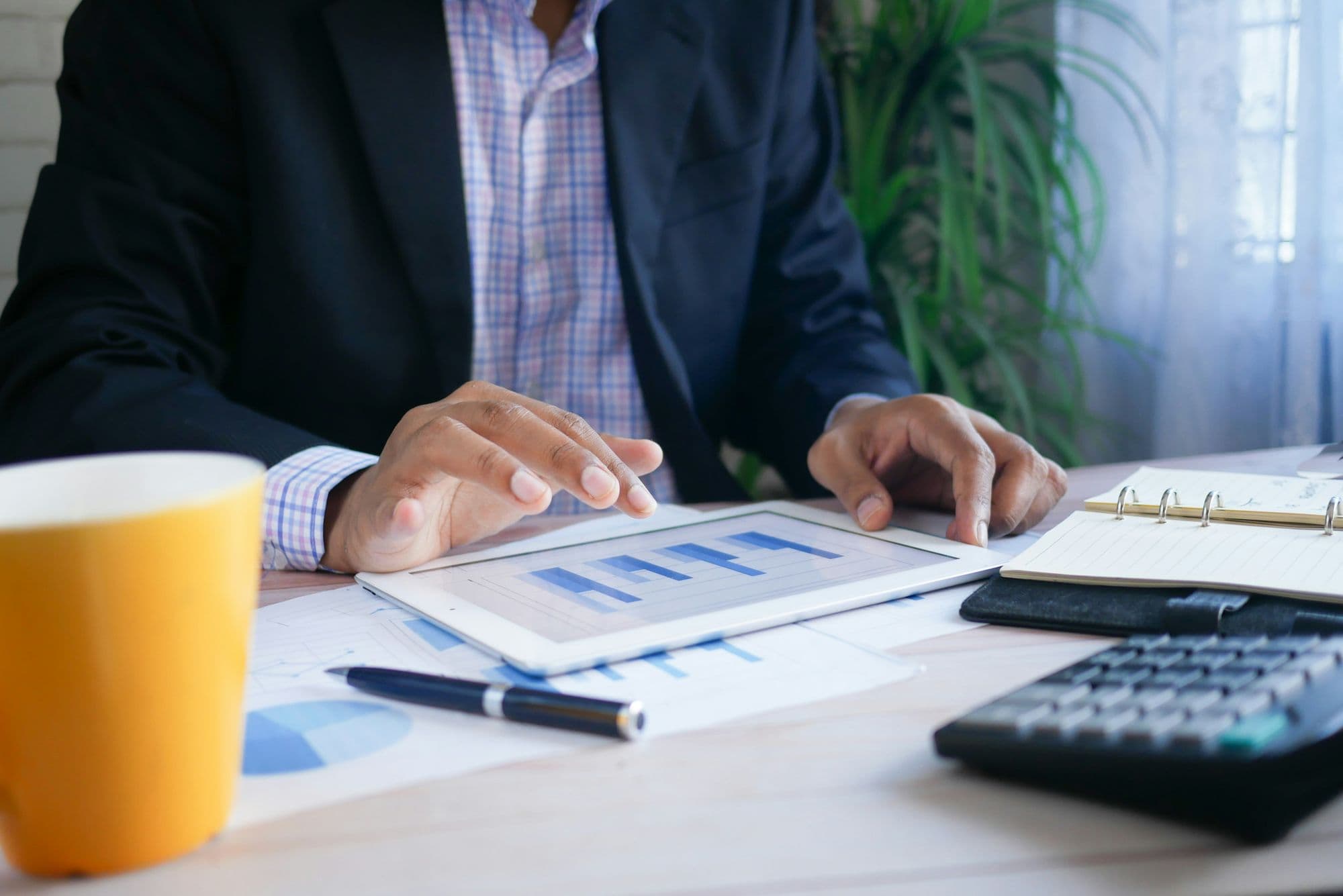 Businessman comparing charts on a tablet and paper reports at a desk